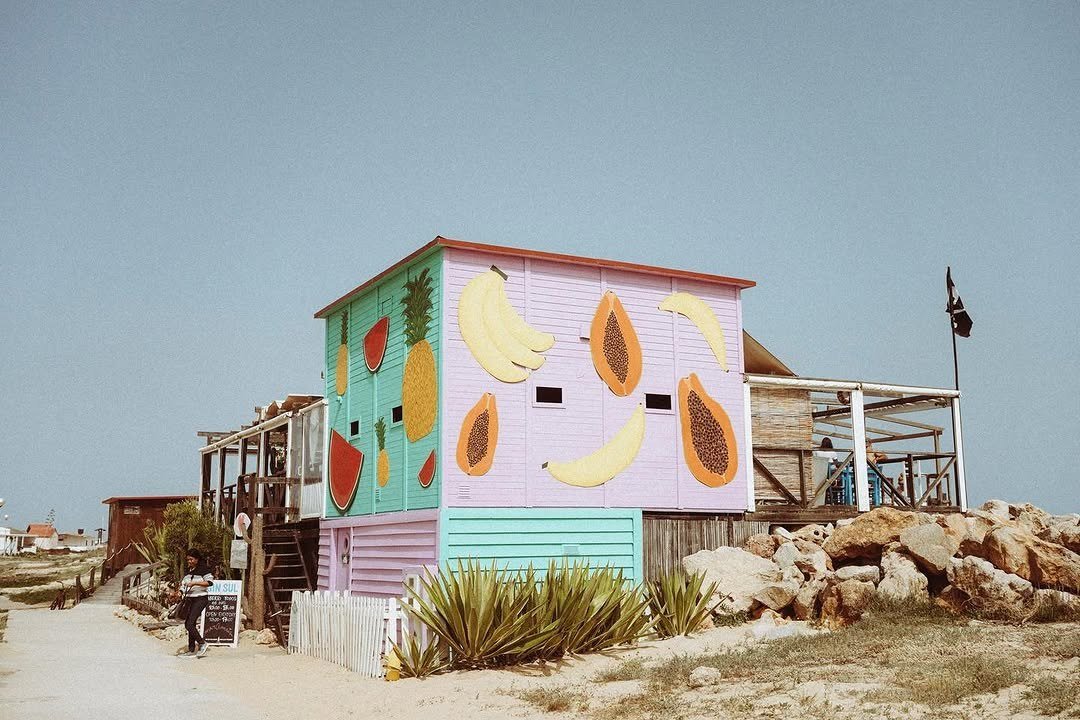 Casinha de madeira pintada com frutas tropicais, junto às dunas da Ilha do Farol